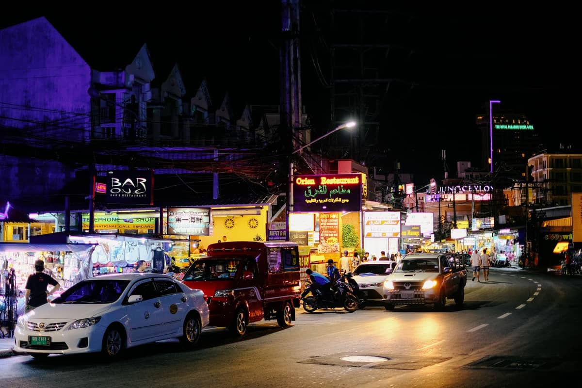 La rue principale d'Ao Nang de nuit avec enseignes lumineuses, bars, circulation et passants, ambiance vie nocturne de Krabi.
