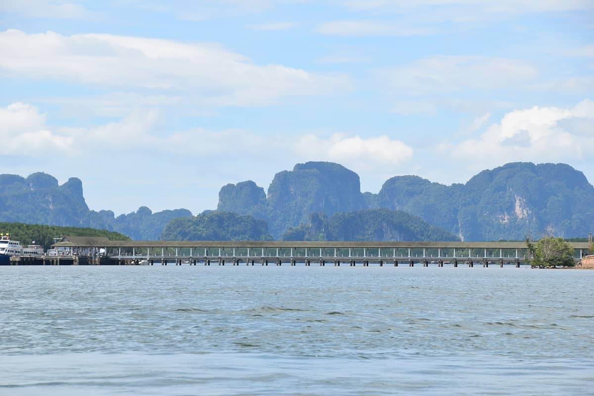 Klong Jilad Pier in Krabi mit angedockten Fähren und Kalksteinfelsen im Hintergrund unter blauem Himmel
