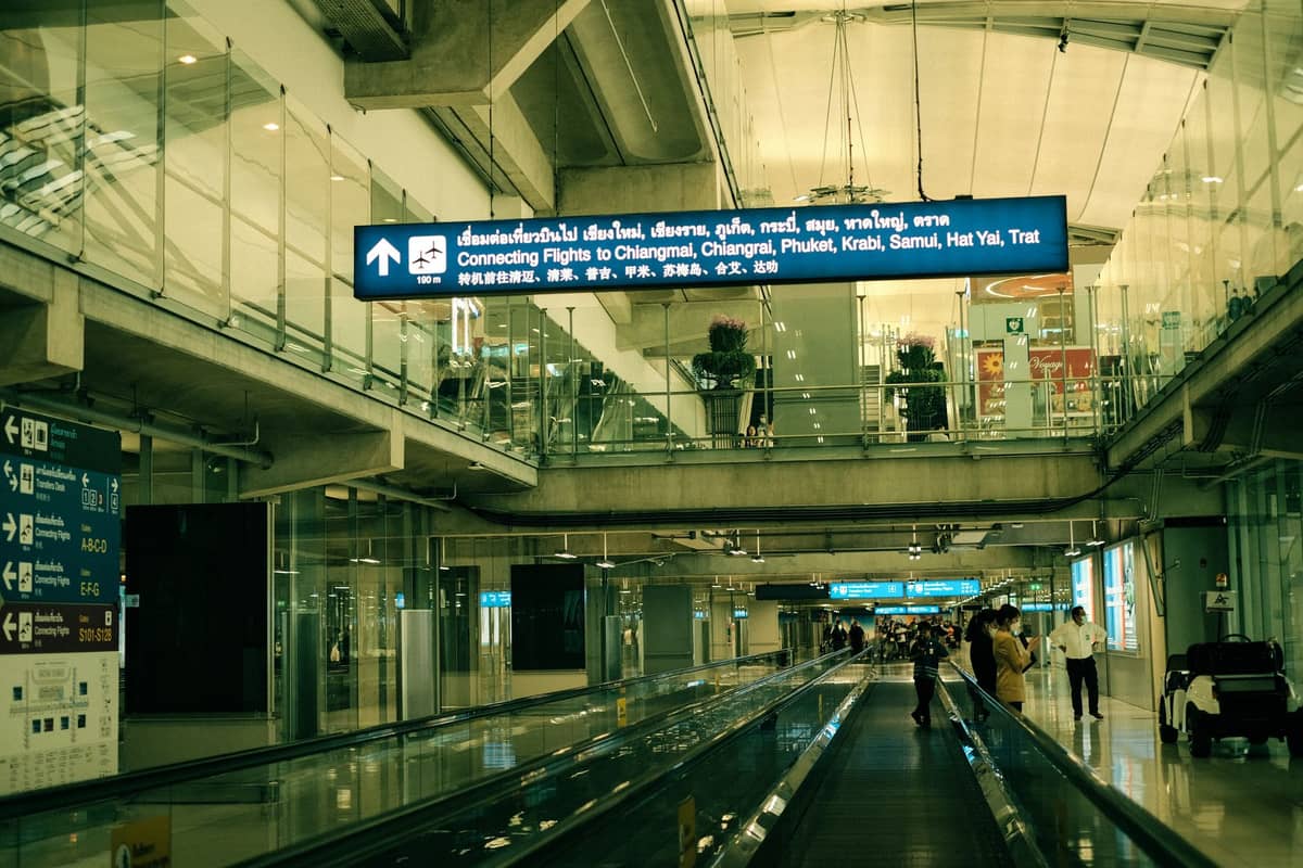 Flughafenterminal von innen mit Schild, das Anschlussflüge nach Krabi, Phuket und andere thailändische Reiseziele anzeigt.