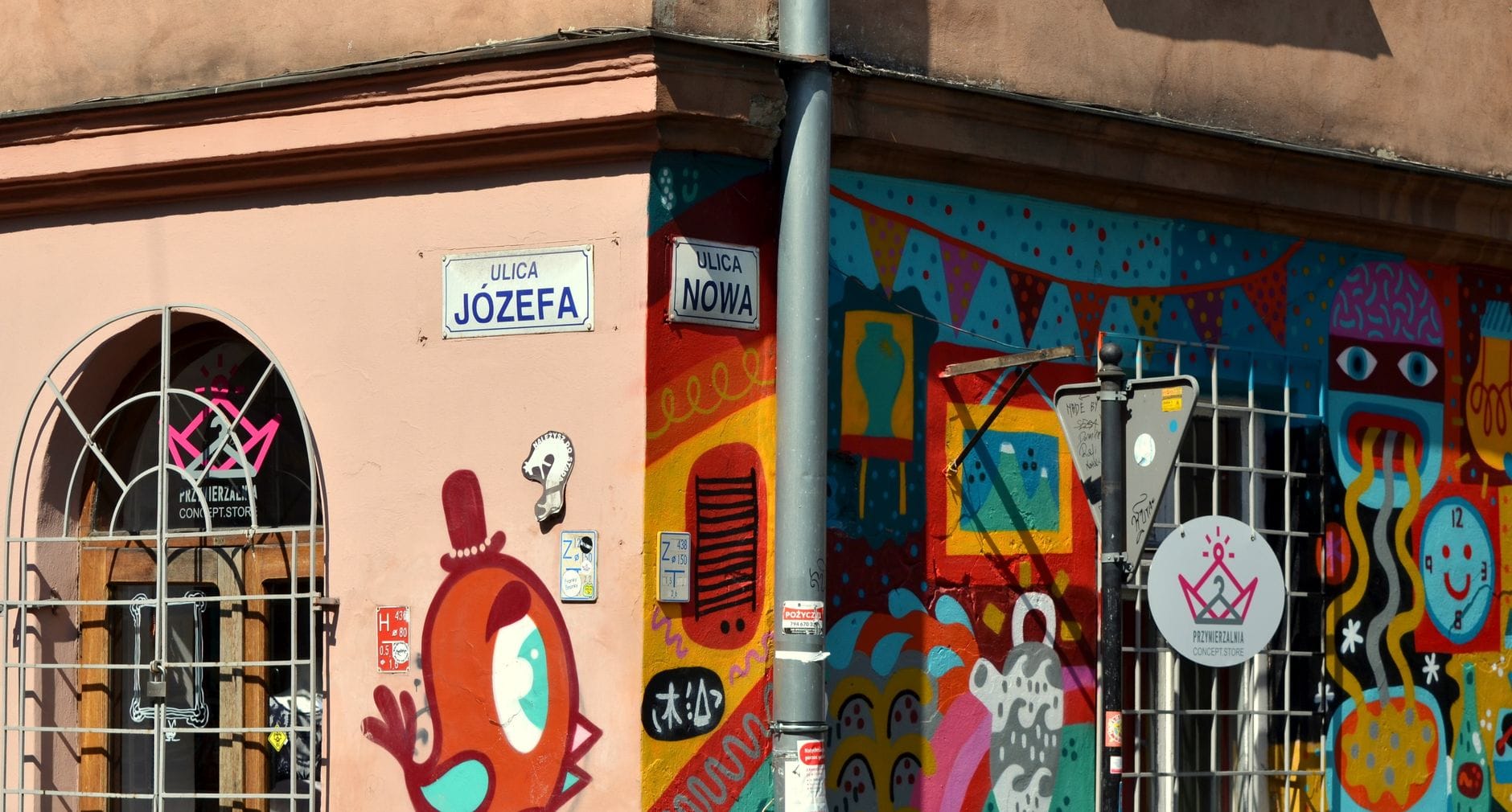 สตรีทอาร์ตสีสันสดใสที่มุมถนน Józefa กับ Nowa ในย่าน Kazimierz ของคราโคว มีป้ายถนนและภาพวาดสร้างสรรค์บนกำแพงอาคาร