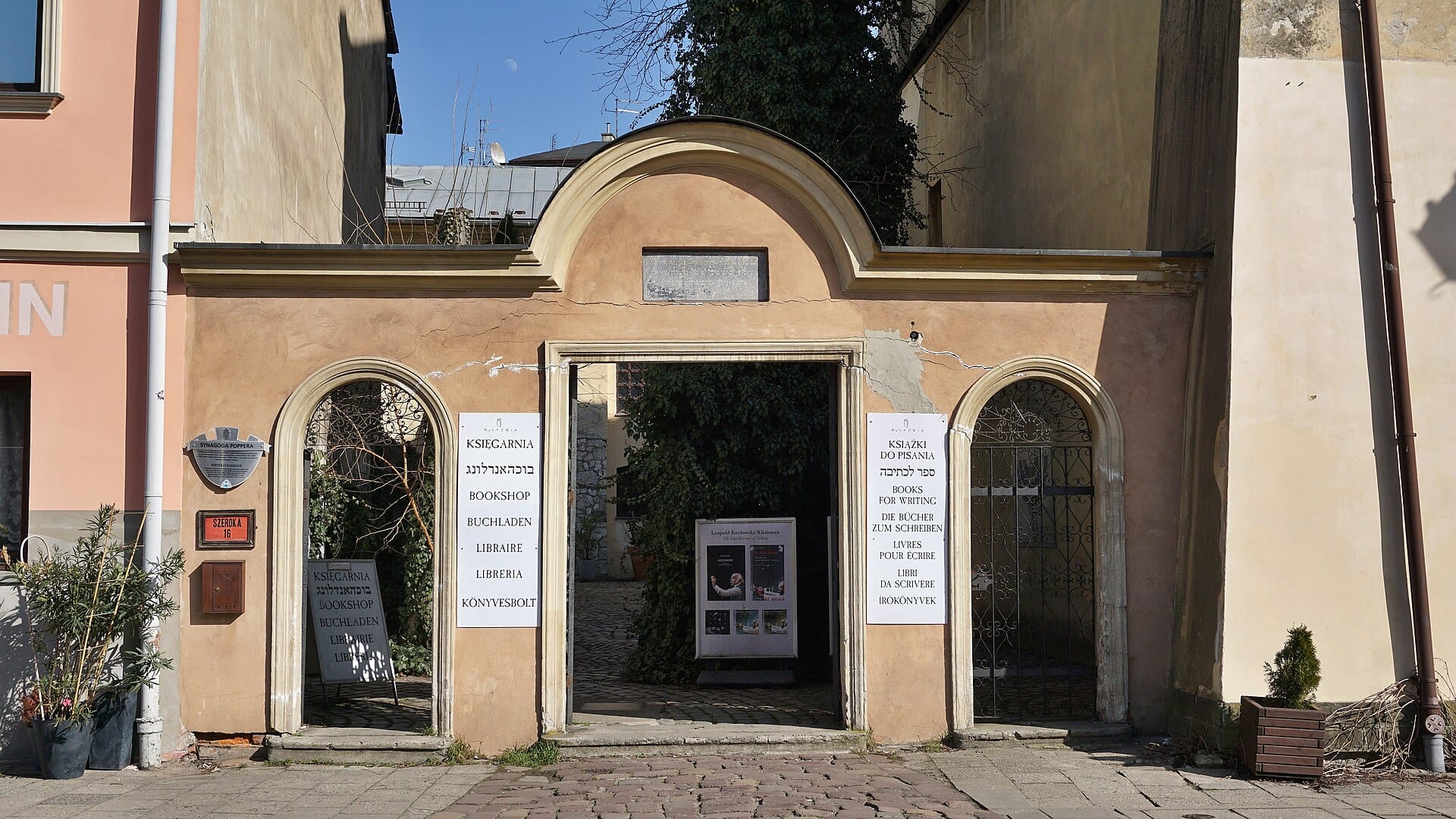 ทางเข้าโบสถ์ยิว Popper ในย่าน Kazimierz เมือง Kraków พร้อมป้ายหลายภาษาและประตูโค้ง
