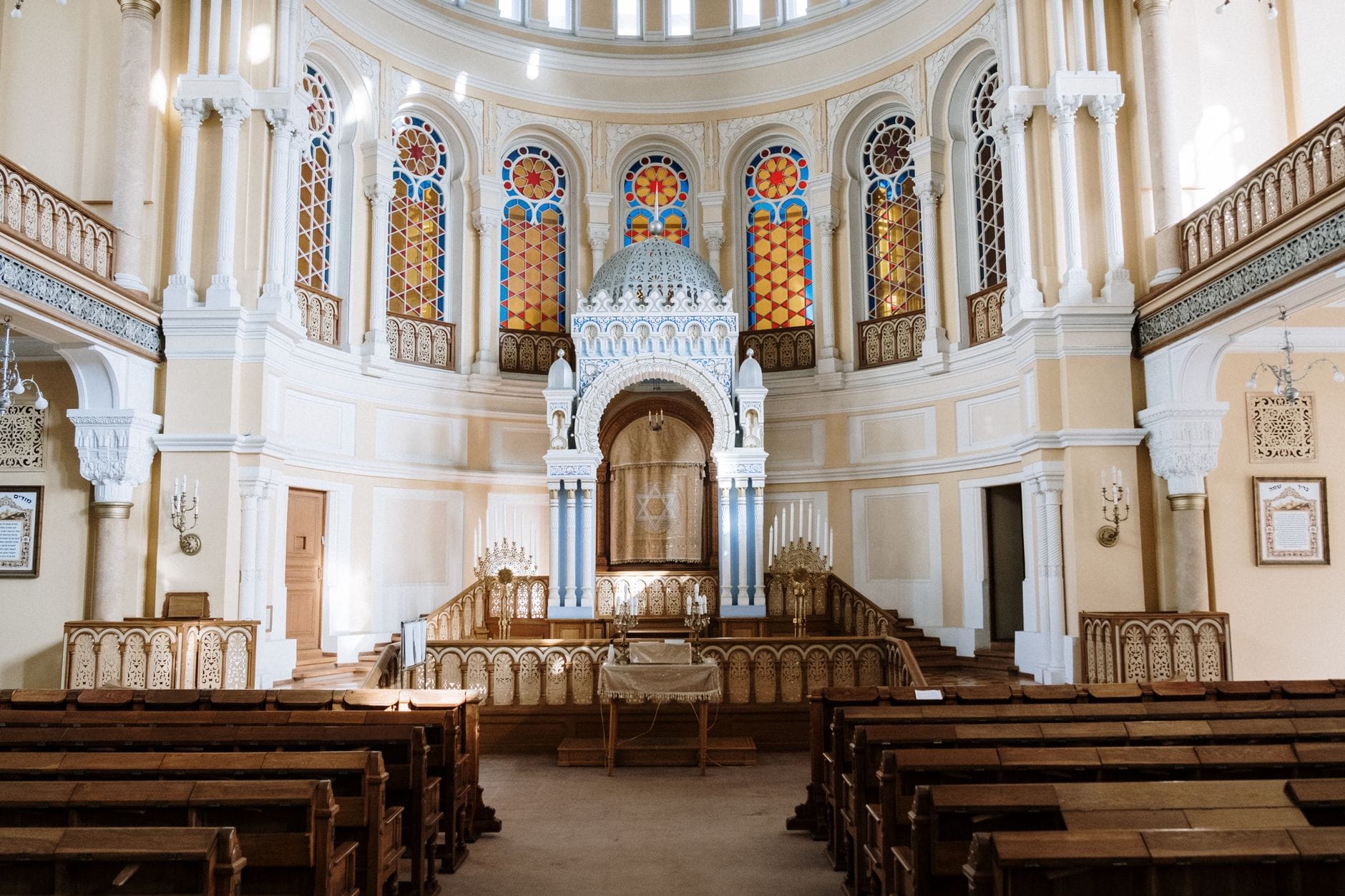 ด้านในโบสถ์ Tempel Synagogue อันวิจิตรในย่านคาซิเมียร์ซของคราคูฟ มีม้านั่งไม้ หน้าต่างกระจกสี และแท่นศักดิ์สิทธิ์ตกแต่งอย่างสวยงาม