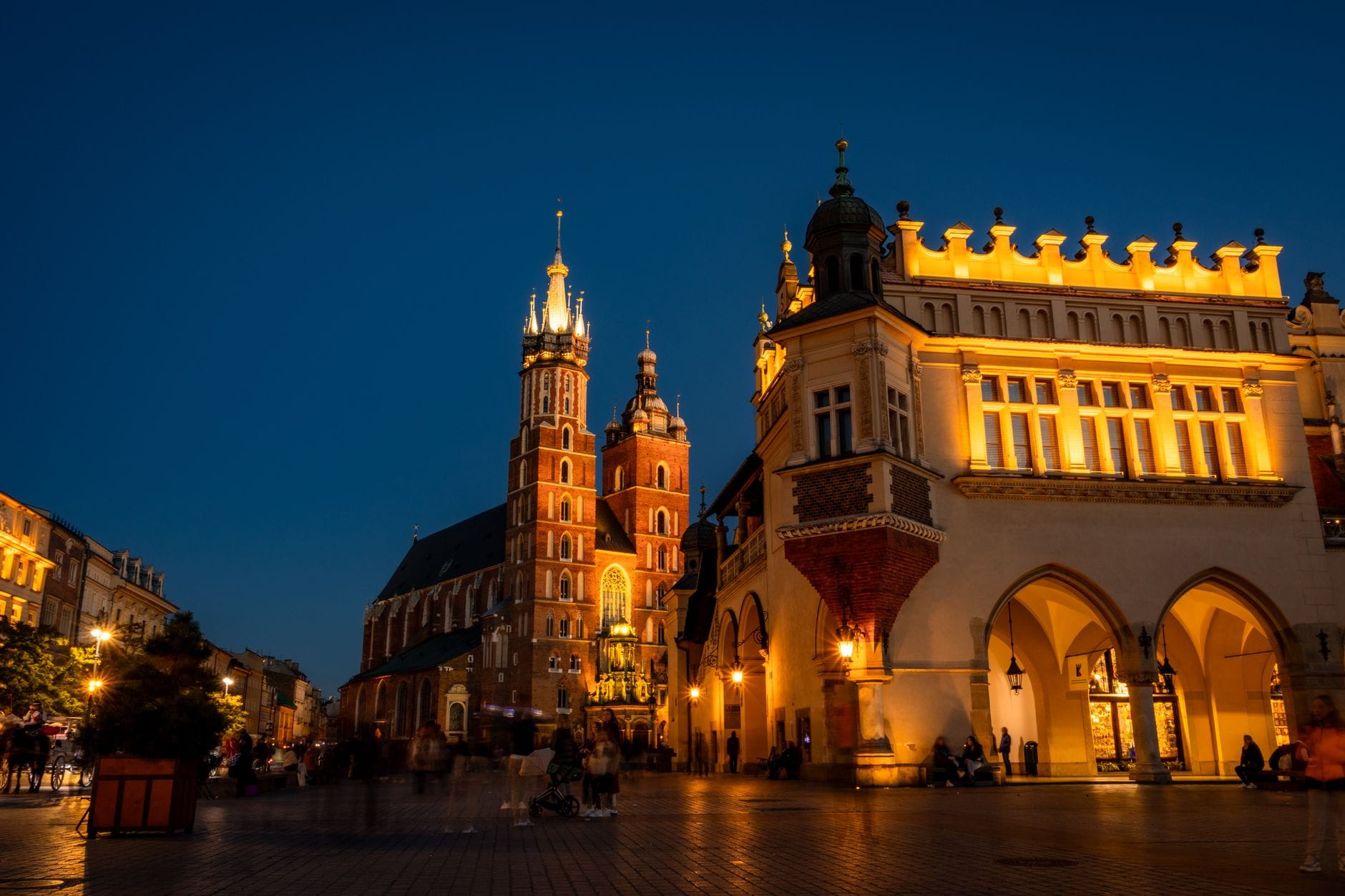 จัตุรัสตลาดหลัก Rynek Główny ของเมือง Kraków ยามค่ำคืน พร้อมภาพมหาวิหาร มหาวิหารเซนต์แมรี่ และ อาคาร Sukiennice ที่สวยงามสุกสว่าง