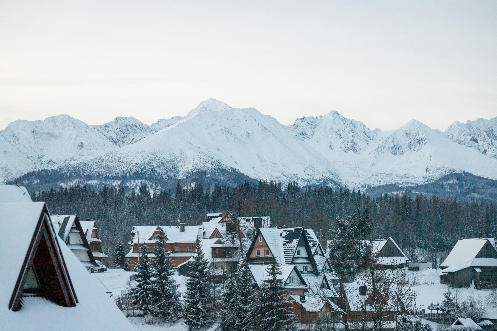 เมือง Zakopane ที่ปกคลุมด้วยหิมะพร้อมบ้านไม้แบบดั้งเดิมและยอดเขา Tatra ที่สง่างามเป็นฉากหลัง ในวันฤดูหนาวที่ท้องฟ้าแจ่มใส