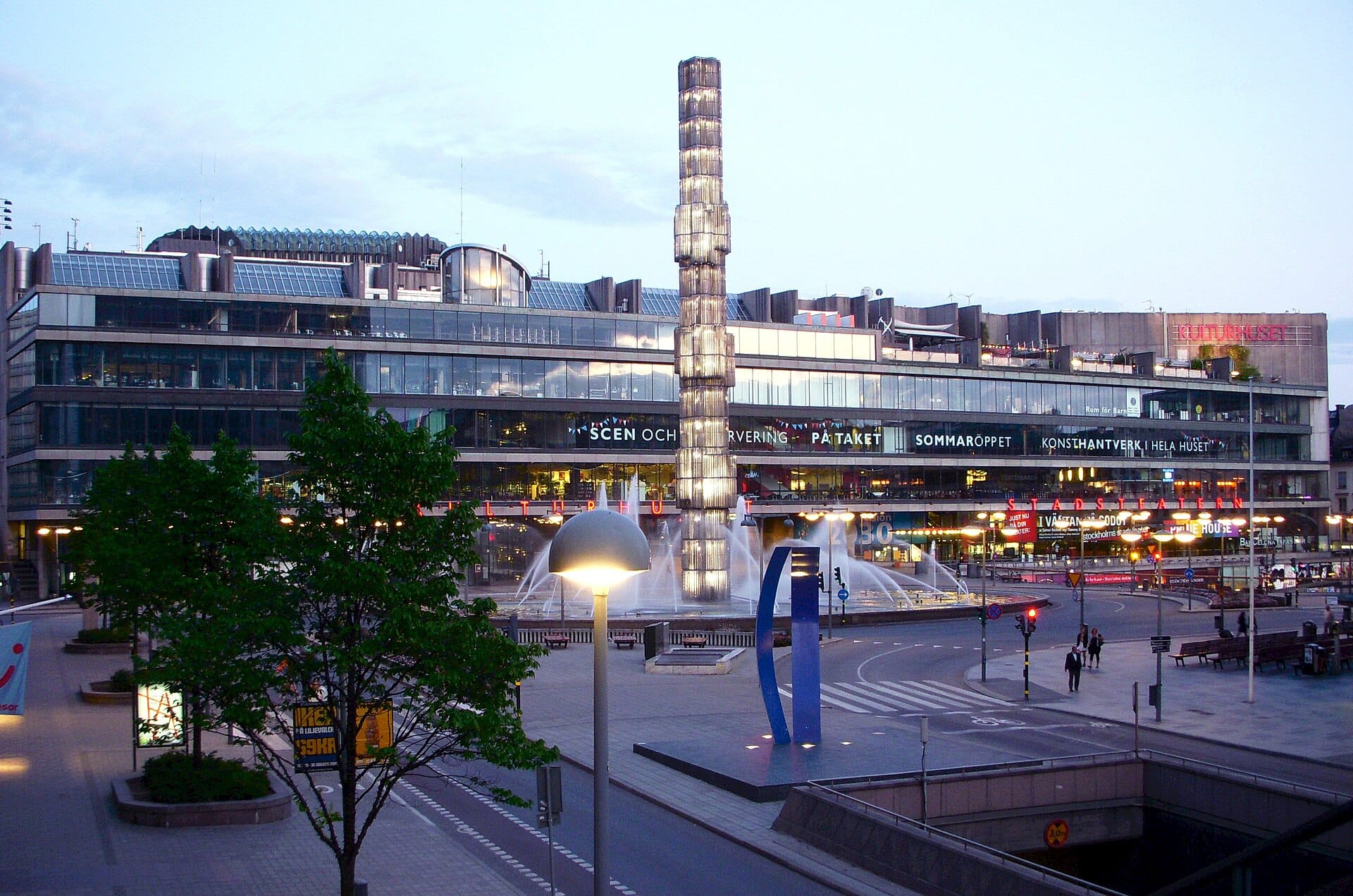 ด้านนอกของ Kulturhuset Stadsteatern ที่ Sergels torg สตอกโฮล์ม เห็นผนังกระจกโมเดิร์นกับลานน้ำพุสว่าง Kristallvertikalaccent