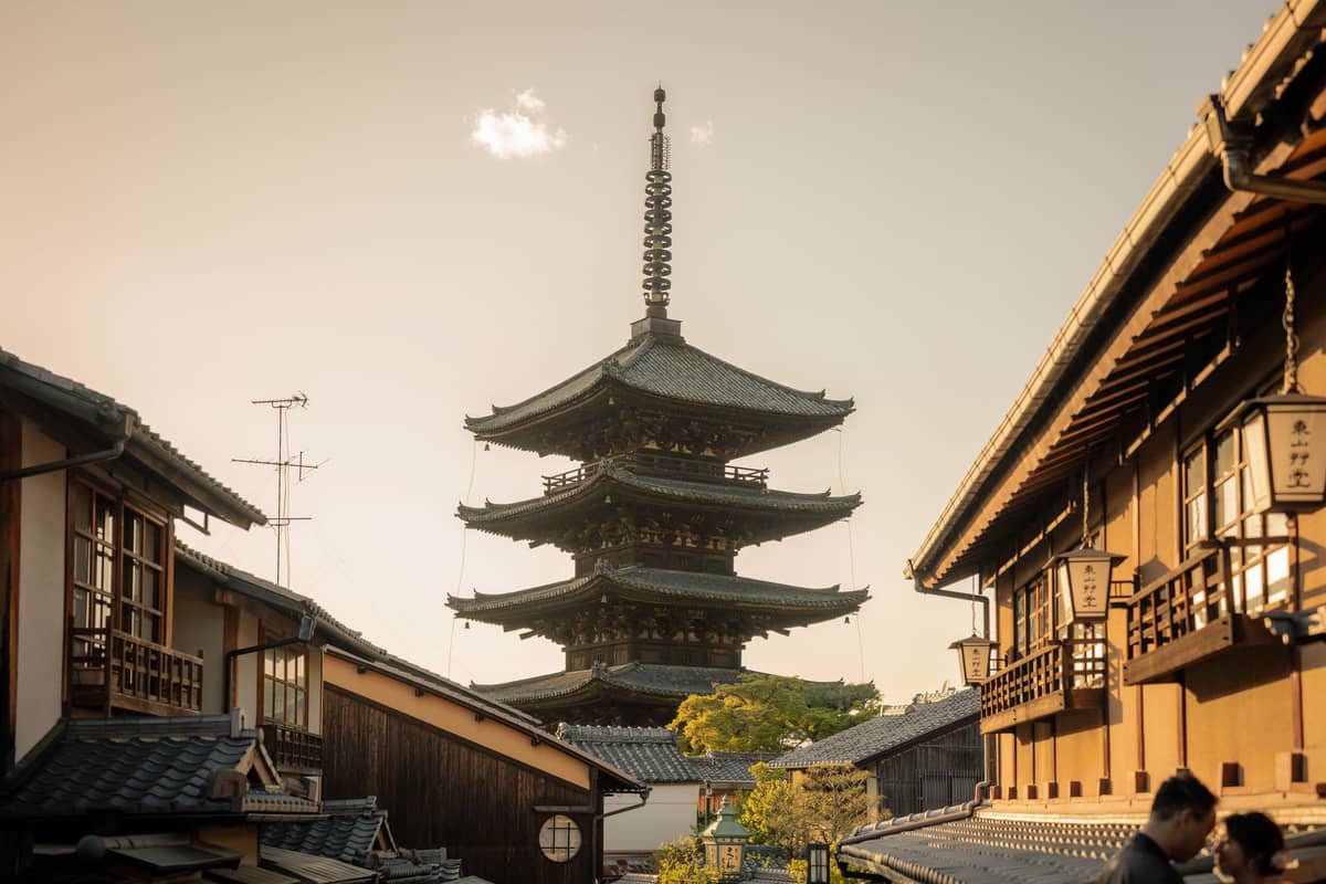 The Yasaka Pagoda rises between traditional wooden machiya townhouses in Kyoto’s historic Higashiyama district at sunset, capturing the city’s classic temple landscape.