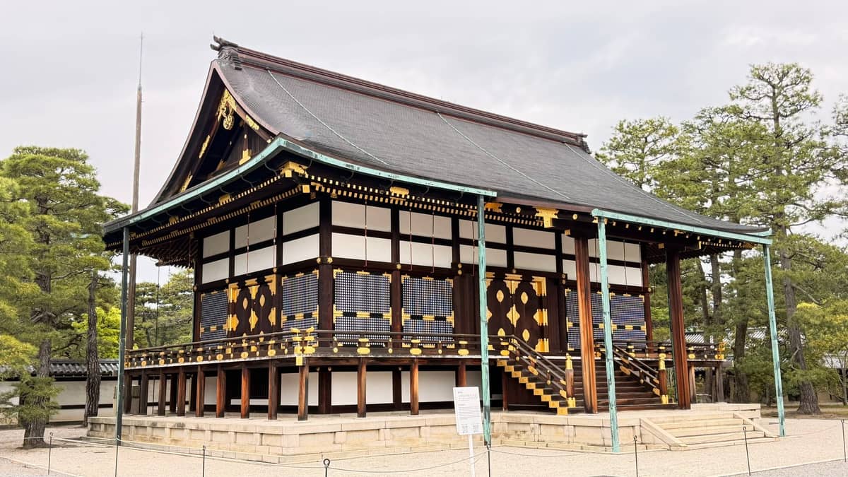 View of Shishinden, the main ceremonial hall of Kyoto Imperial Palace, featuring raised wooden structure, gold details, and gravel courtyard.