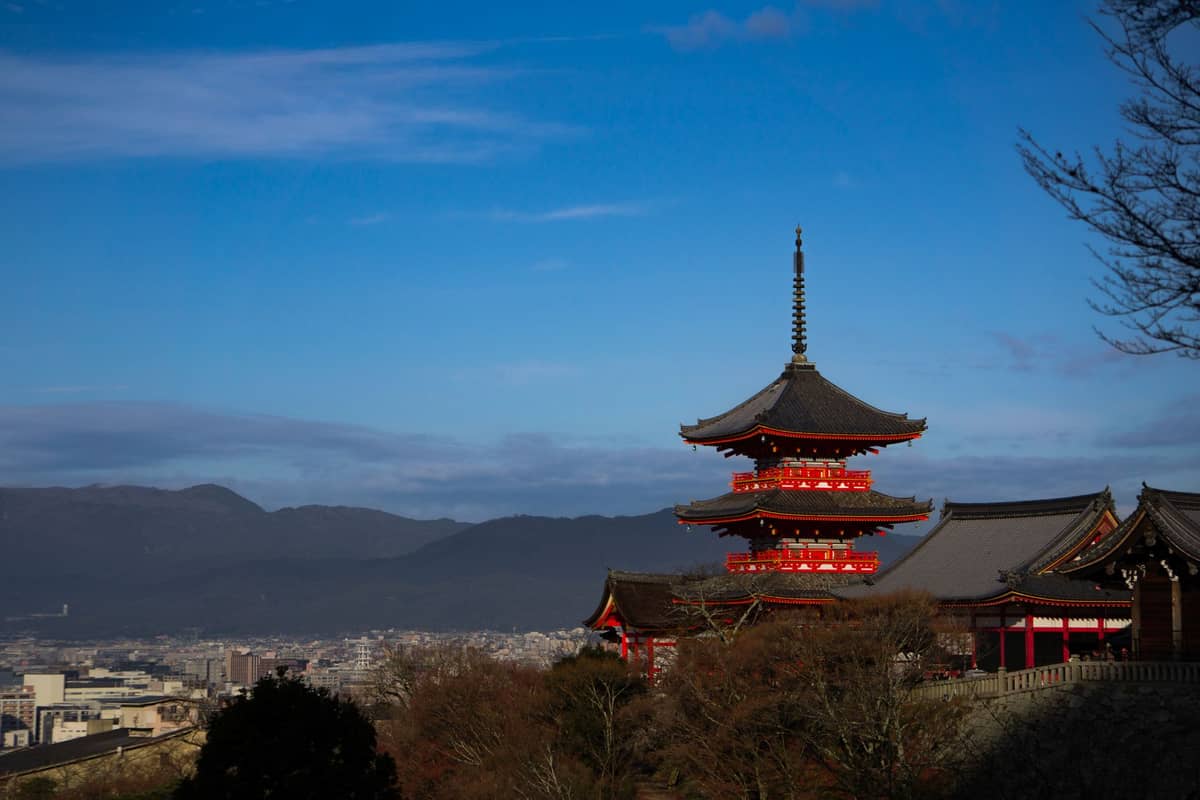 Kyoto cityscape with Kiyomizudera temple and surrounding mountains under clear winter sky.