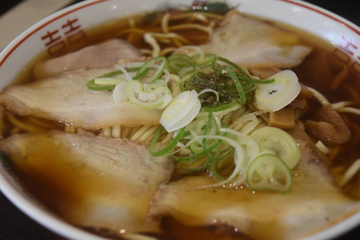 Bowl of ramen with light shoyu broth, sliced pork, scallions, and classic Japanese ramen bowl design on the rim.
