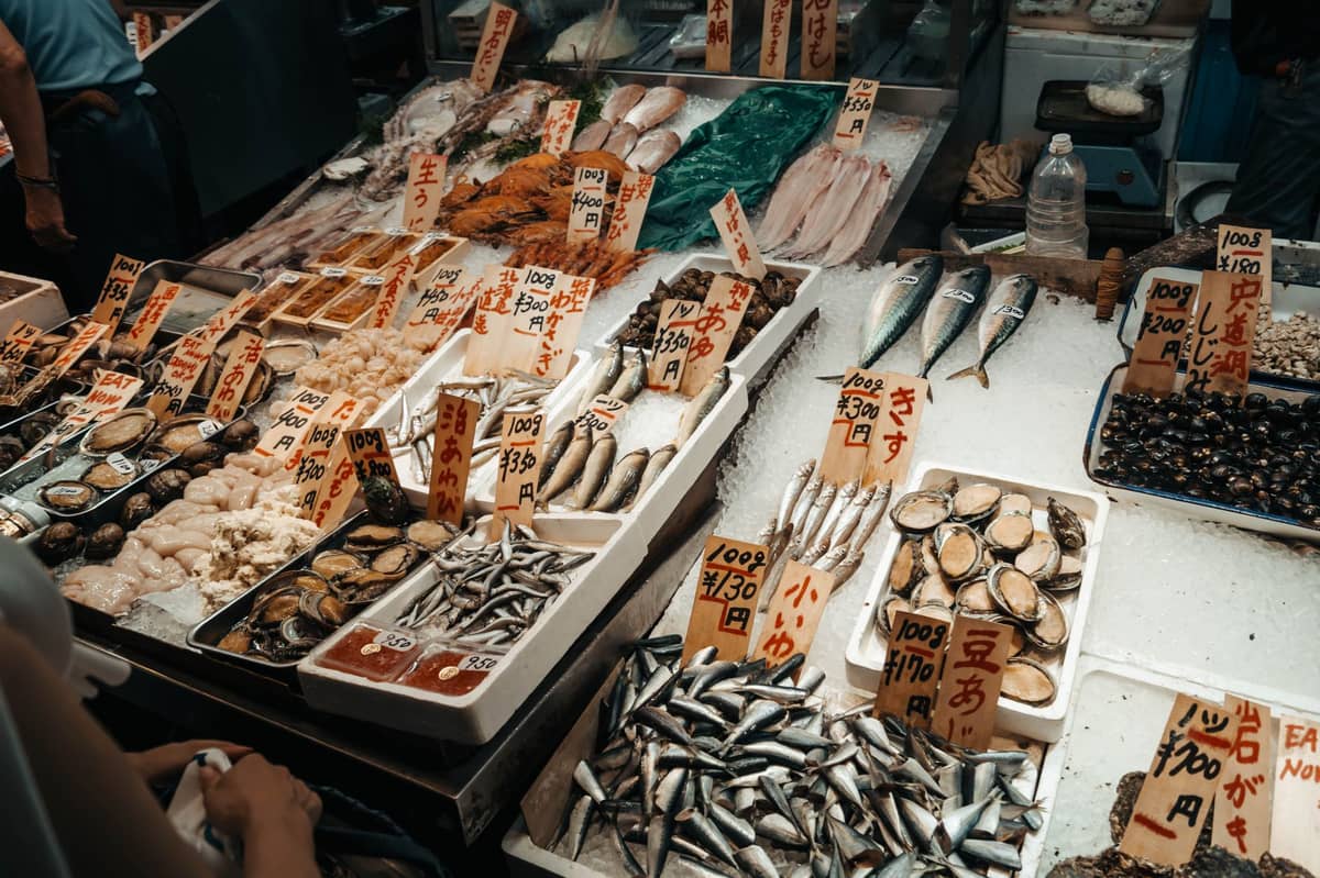 Assorted fresh seafood and fish displayed in a Japanese market, with handwritten price tags in Japanese yen.