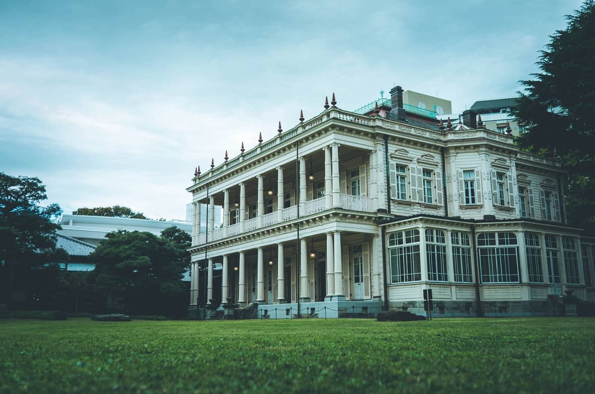 Victorian-style wooden mansion of Kyu-Iwasaki-tei Garden surrounded by greenery and lawn in Tokyo’s Ikenohata area, photographed from a low angle on a cloudy day.
