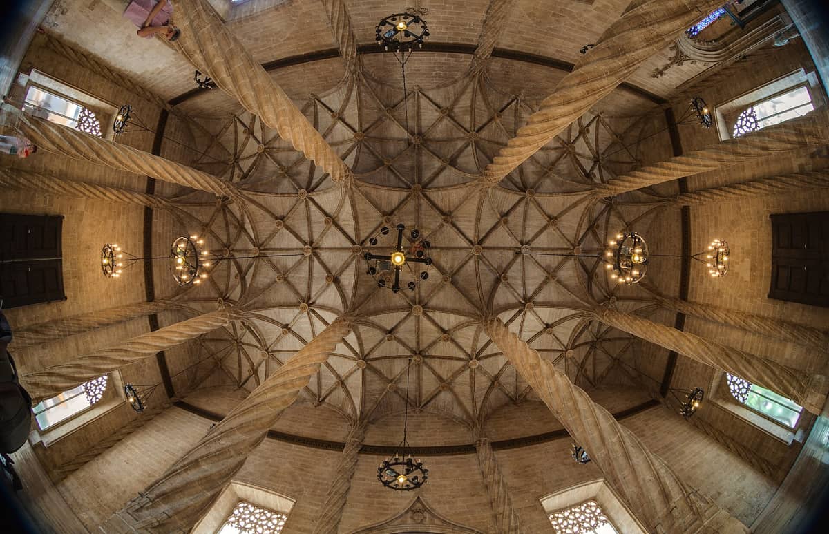 Vista grandangolare dell'iconico interno della Sala de Contratación nella Lonja de la Seda, con le celebri colonne tortili in pietra e la volta gotica nervata.
