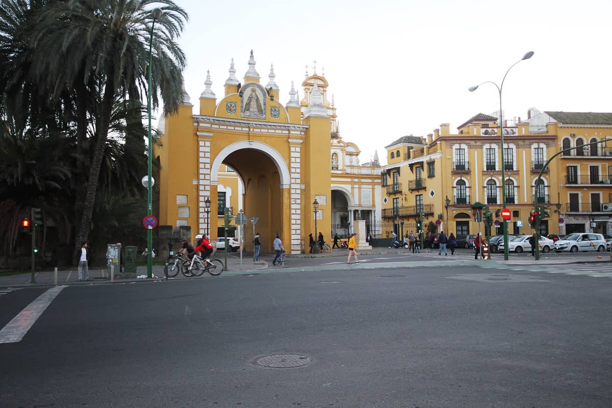 ภาพถนนระดับสายตาที่เห็นประตู Arco de la Macarena และมหาวิหาร Basilica de la Macarena พร้อมผู้คนและรถราบนถนนในย่านลา มากาเรนา เมืองซีบียา
