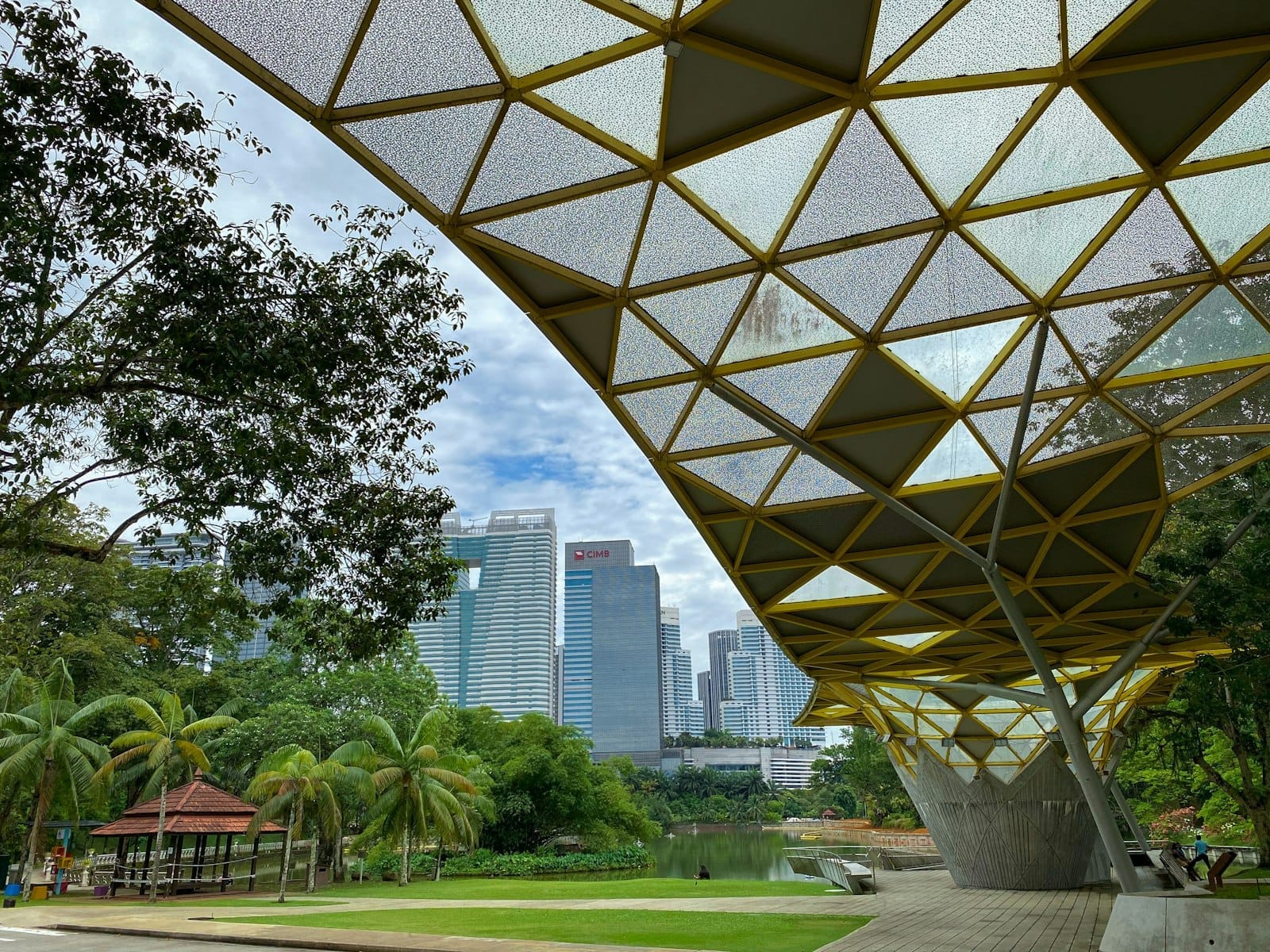 Kuala Lumpur Lake Gardens with geometric canopy walkway, lush greenery, and KL skyline in the background