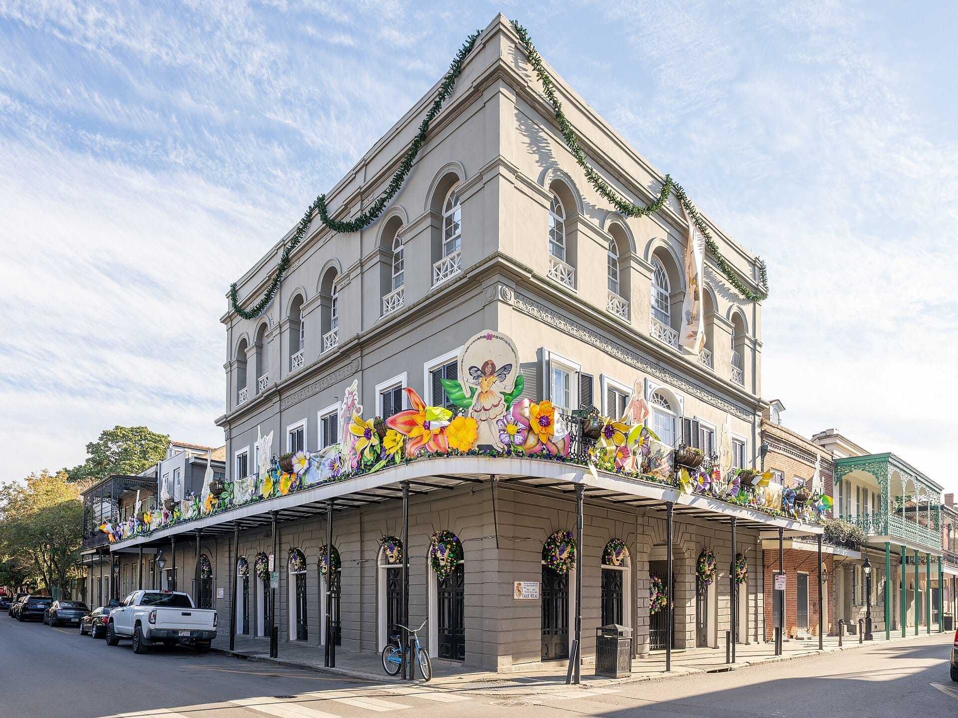 Vista della storica LaLaurie Mansion a New Orleans, un edificio grigio di tre piani con finestre ad arco e decorazioni floreali festive sul balcone.