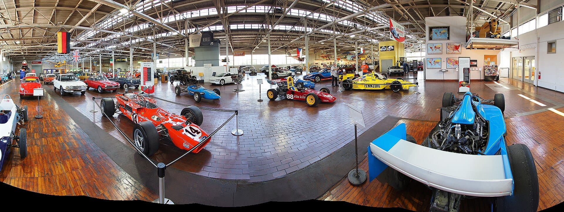Vista amplia de autos de carrera vintage y vehículos clásicos exhibidos en el espacioso y luminoso salón industrial del Lane Motor Museum en Nashville.