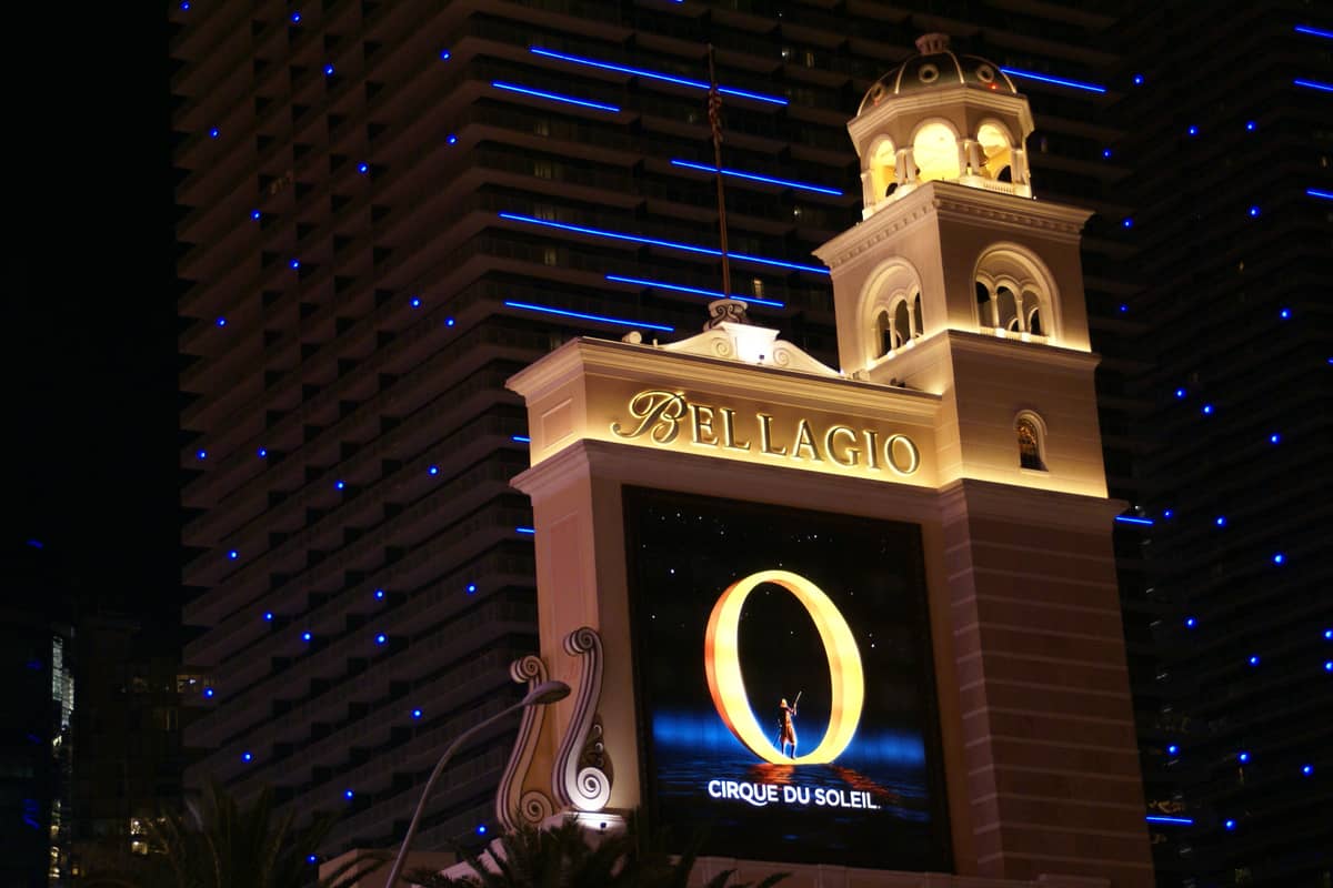 Vista nocturna del Bellagio Hotel con un cartel iluminado que anuncia el espectáculo 'O' de Cirque du Soleil, una experiencia emblemática para parejas.
