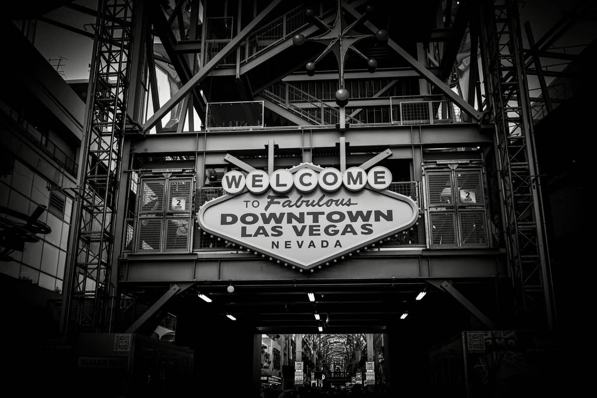 Black and white photo of the Welcome to Fabulous Downtown Las Vegas Nevada sign under metal framework, marking entrance to Fremont Street area.