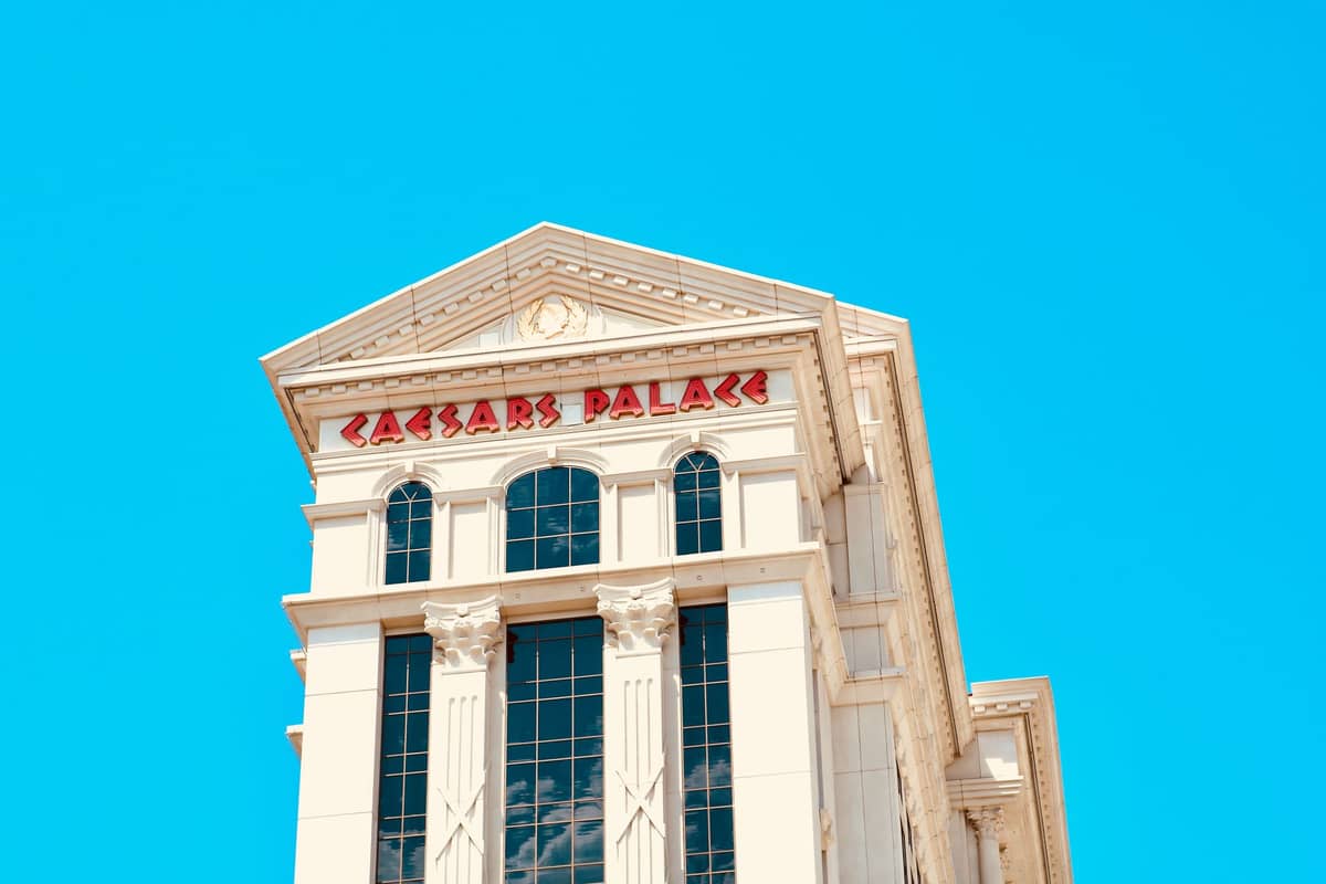 Die Spitze des Caesars Palace in Las Vegas mit seiner ikonischen Säulenarchitektur und dem roten Caesars Palace-Schriftzug vor einem klaren blauen Himmel.