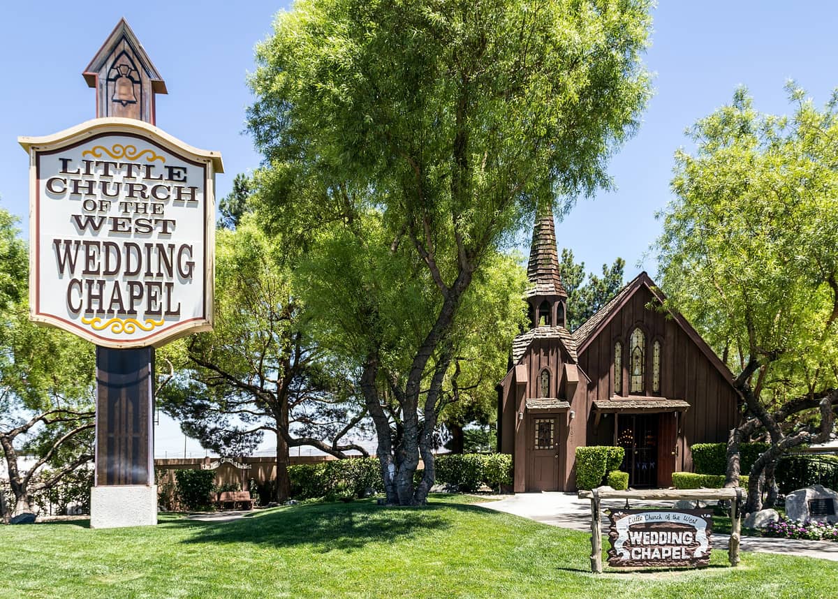 L'extérieur de la Little Church of the West Wedding Chapel à Las Vegas, avec une signalétique bien visible et entourée d'arbres verts et de pelouse.