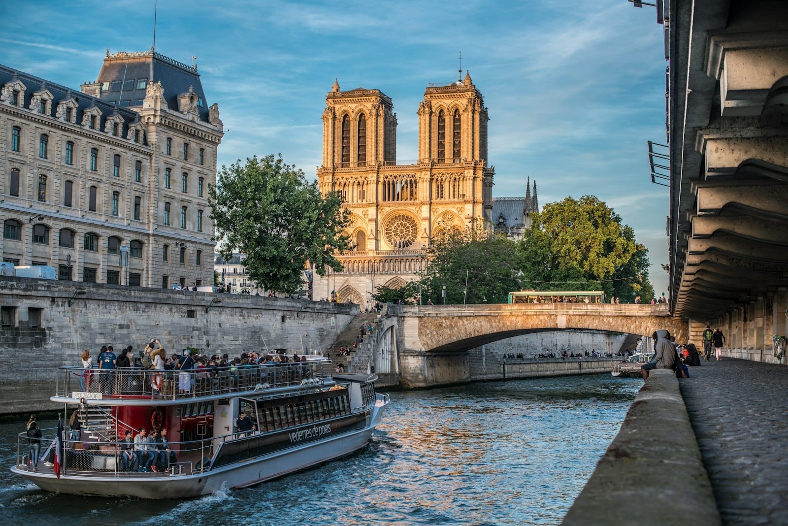Vista di Notre-Dame e della Senna durante l'ora dorata, con un battello e passanti che catturano lo spirito vivace del Quartiere Latino.