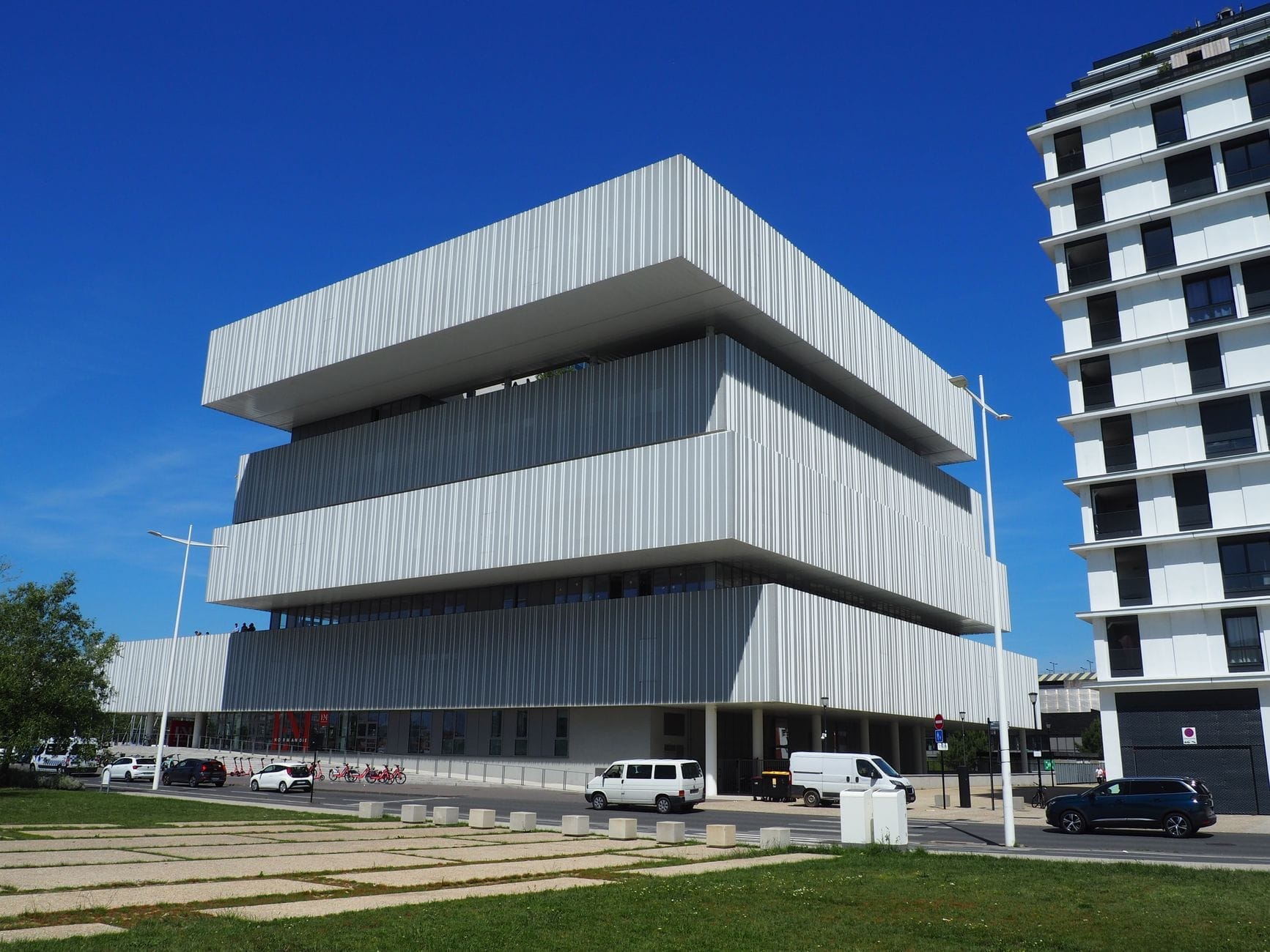Le Havre'da güneşli bir günde açık mavi gökyüzü altında yatay katmanları ve geniş pencereleri olan modern, köşeli bir bina.