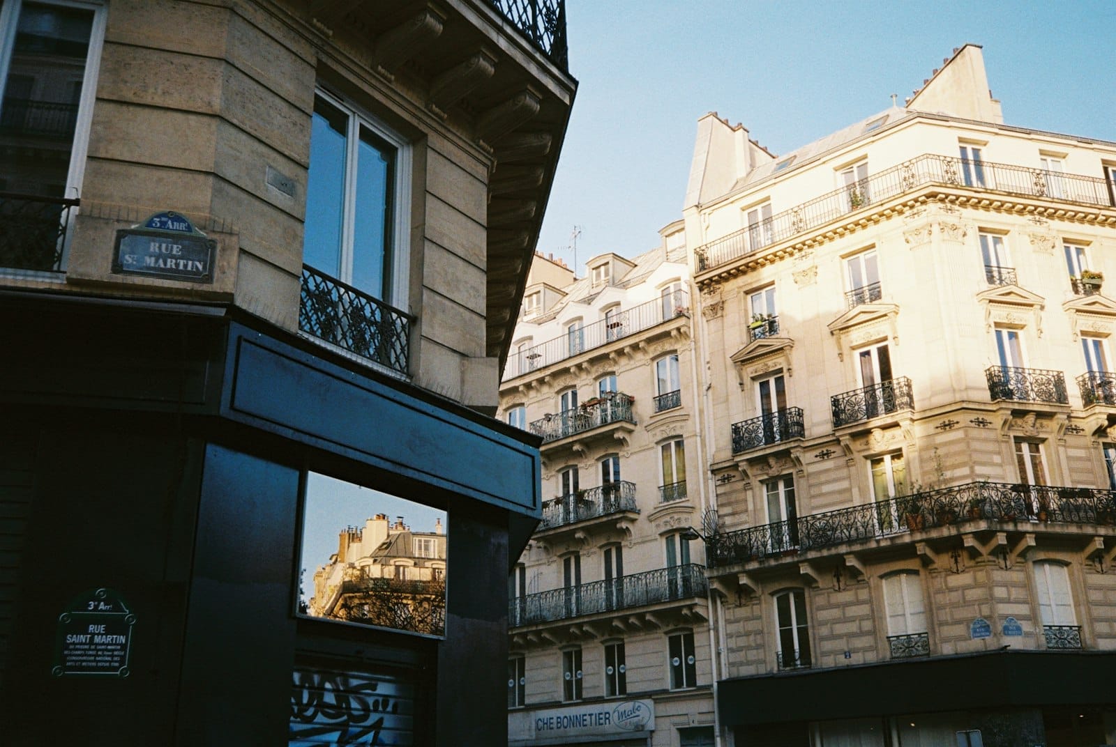 Eleganti edifici parigini nel quartiere Le Marais immersi nella luce calda del pomeriggio, con i cartelli di Rue Saint-Martin e facciate raffinate che raccontano il fascino di questo quartiere storico.