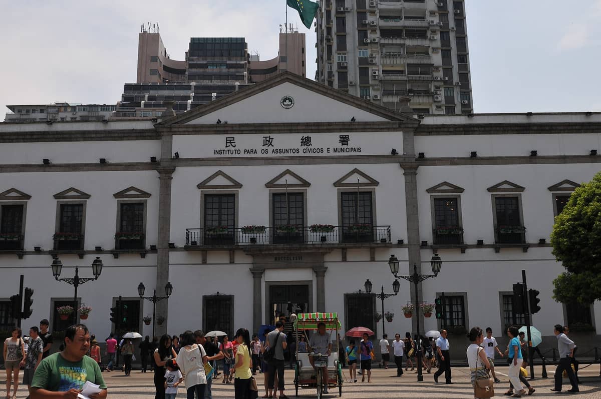 Frontansicht des Leal Senado Gebäudes in Macau mit seiner neoklassischen Fassade und Menschen auf dem Senado-Platz an einem sonnigen Tag.