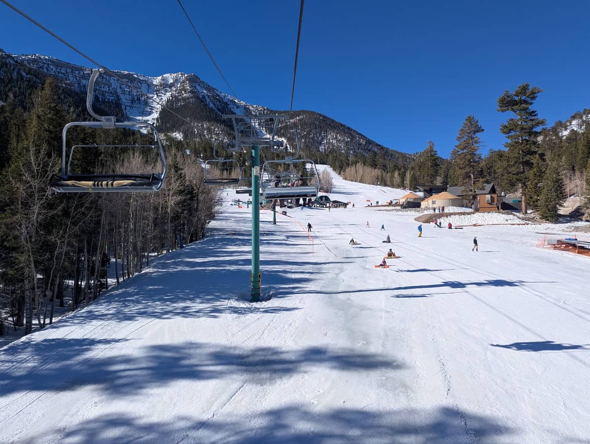 Teleférico e pistas no Lee Canyon Ski Resort com paisagem nevada, pinheiros e esquiadores aproveitando um dia de inverno ensolarado perto de Las Vegas.