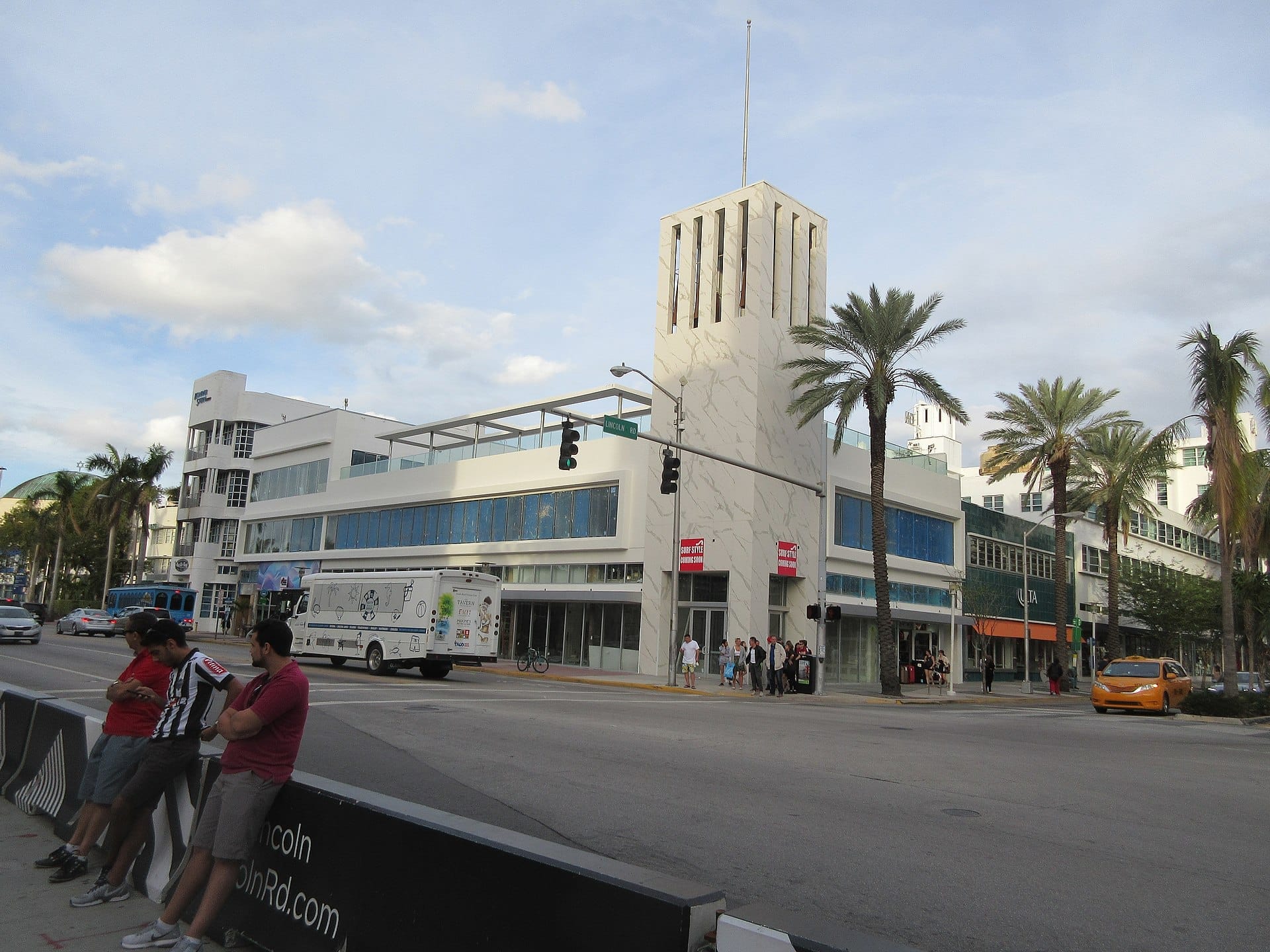 Edifici Art Déco, palme e pedoni animano il vivace Lincoln Road Mall a South Beach sotto un cielo parzialmente nuvoloso.
