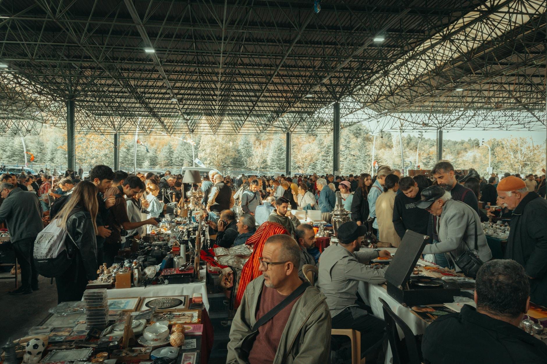 Marché aux puces couvert et animé avec de nombreuses personnes parcourant des stands remplis d'antiquités et d'articles vintage à Lisbonne.