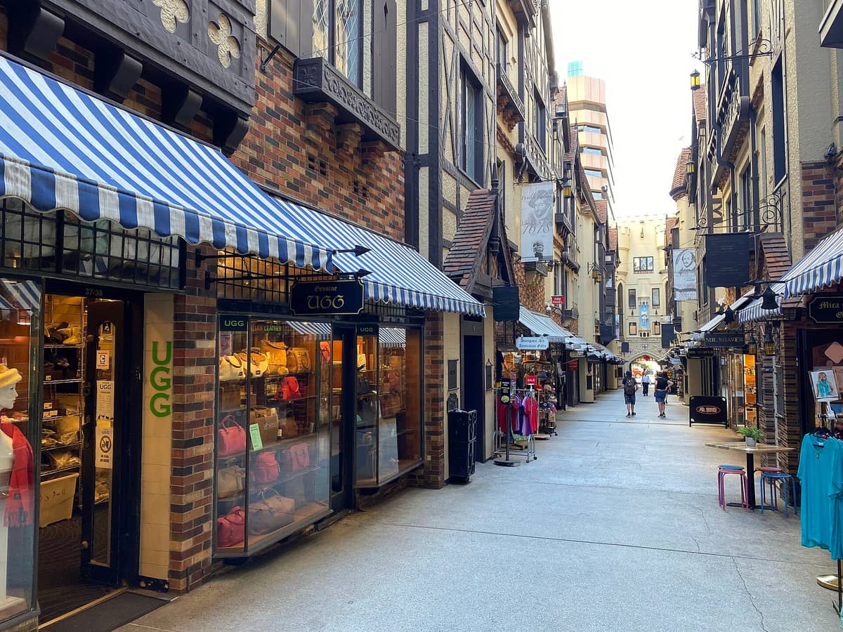 Vista del interior de la arcada London Court en Perth, con fachadas de estilo Tudor, frentes de tiendas con toldos a rayas y paseantes caminando por el pasillo.