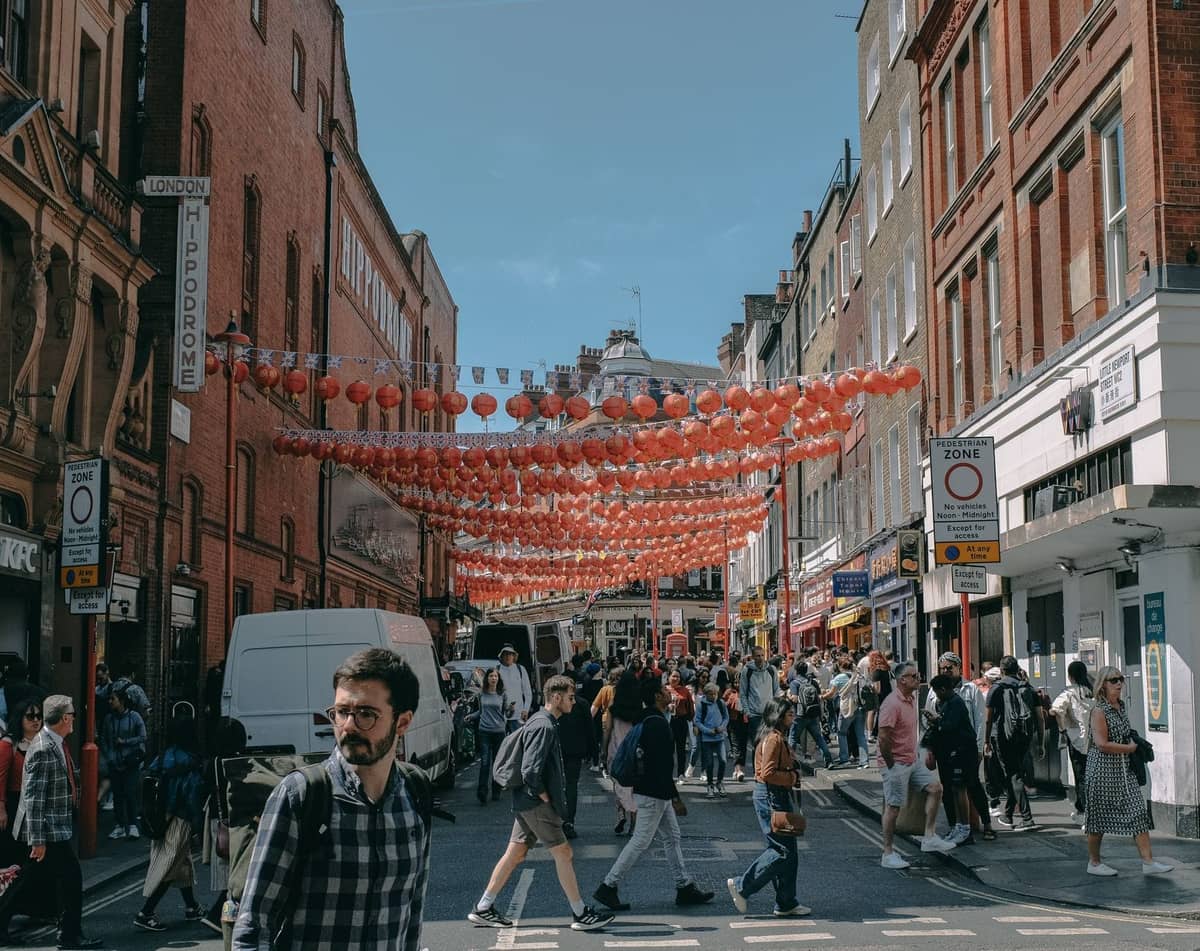 Movimentada cena de rua em Londres com lanternas vermelhas suspensas, pedestres e uma atmosfera urbana vibrante.