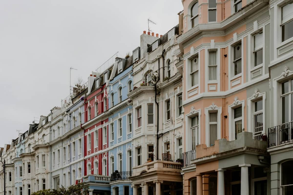 Fileira de casas geminadas clássicas em cores pastel numa rua de Londres sob um céu nublado, mostrando o carácter dos bairros de Londres.