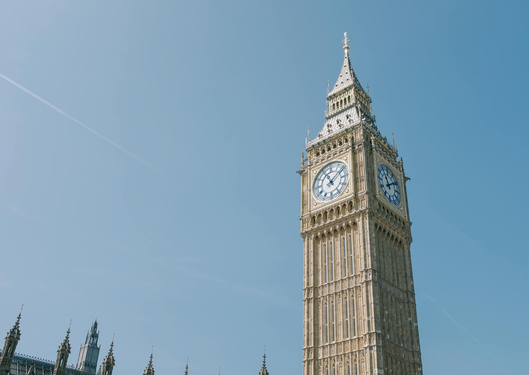 Vista panorâmica do Big Ben e do Palácio de Westminster sob um céu azul, um dos cartões-postais mais icônicos de Londres para quem visita pela primeira vez.