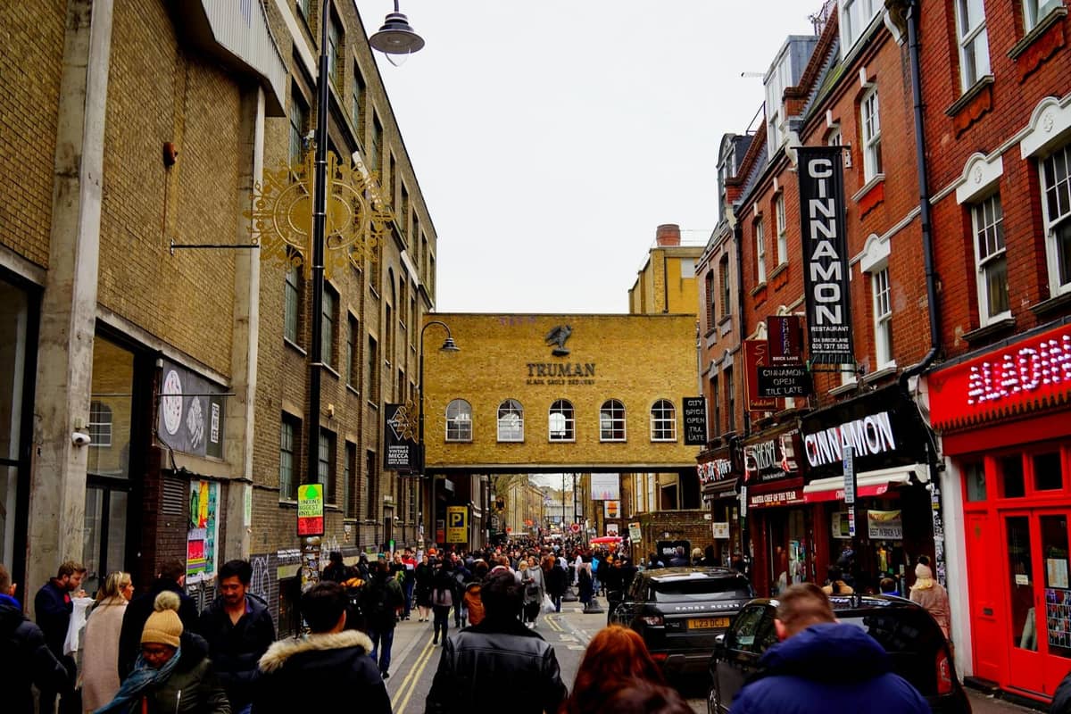Movimentada cena de rua em Londres na Truman Brewery em Brick Lane, ladeada de lojas e pessoas, capturando a atmosfera do mercado local.