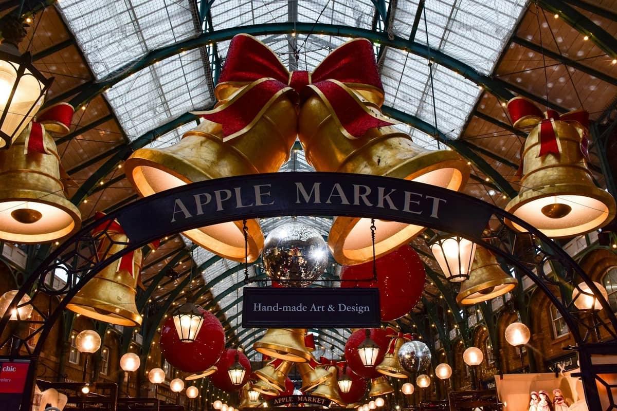 O Apple Market do Covent Garden em Londres, decorado com grandes enfeites natalinos e laços sob um teto de vidro.