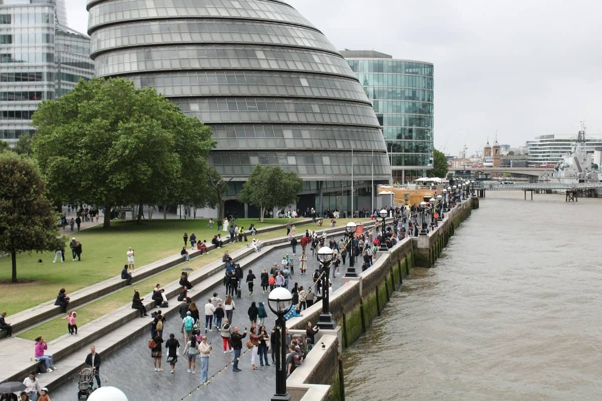 Pessoas caminhando ao longo do Tâmisa perto do London City Hall em um suave dia de verão nublado