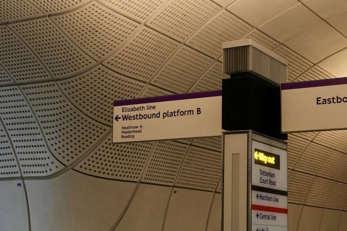 Sinalização em uma plataforma da Elizabeth line de Londres indicando trens em direção a Heathrow e estações centrais, em uma moderna estação de metrô.