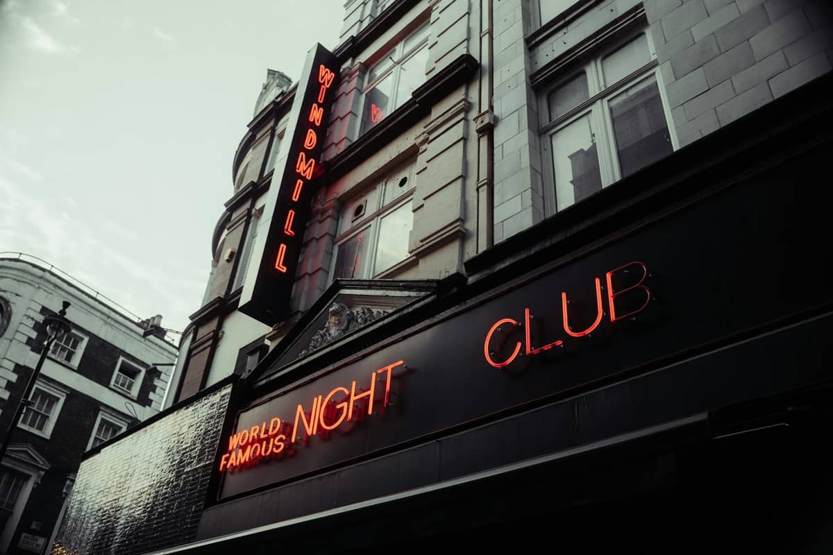 Exterior do Windmill Night Club em Londres com letreiros de néon acesos ao anoitecer
