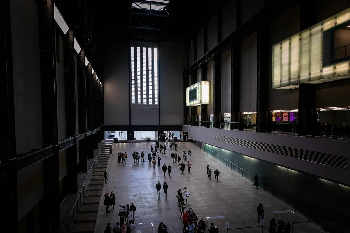Vista ampla do Turbine Hall do Tate Modern com visitantes caminhando e se reunindo no icônico museu de arte de Londres.