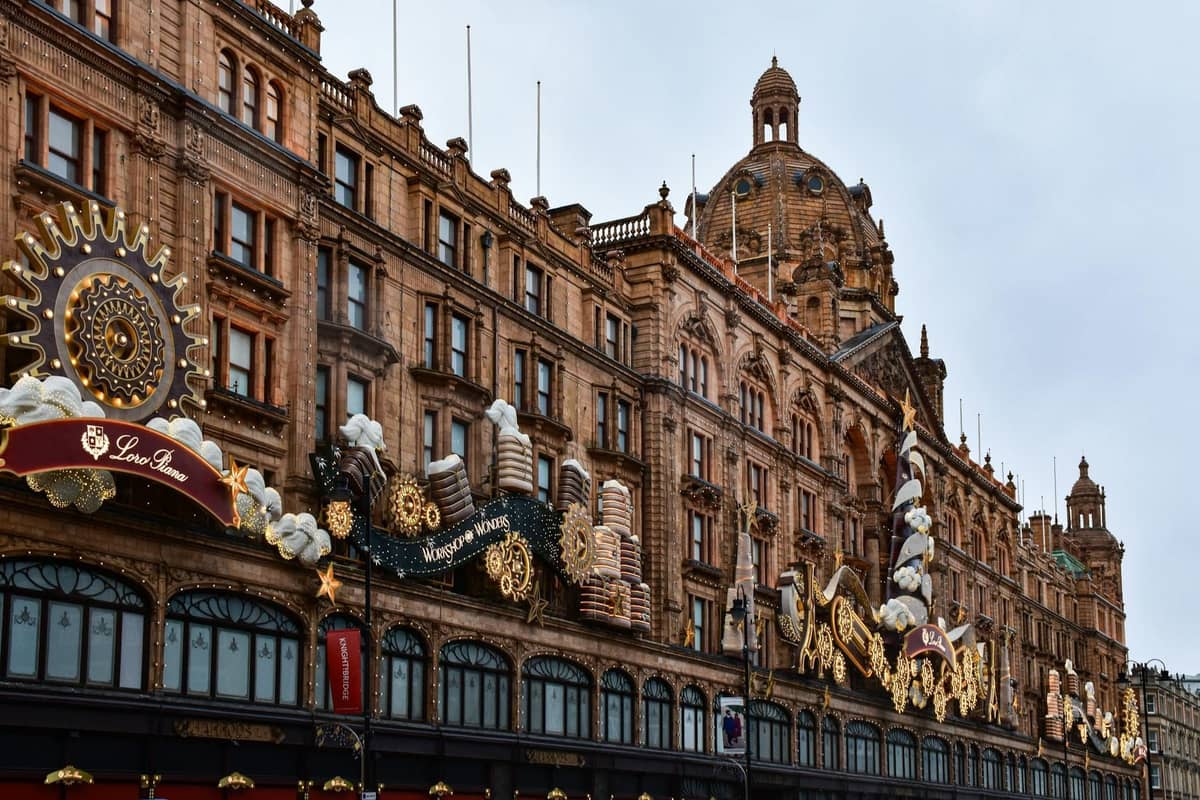 Vista ampla dos grandes armazéns Harrods em Londres, ricamente decorados e movimentados, mostrando claramente a sua arquitetura icónica.