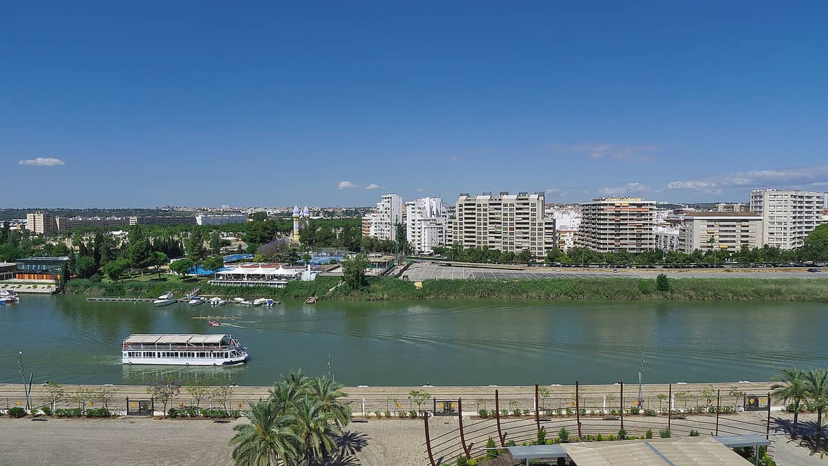 วิวกว้างย่าน Los Remedios เห็นอาคารสมัยใหม่ ถนนใหญ่ปลูกต้นไม้เรียงราย และแม่น้ำ Guadalquivir ขึ้นหน้า ท้องฟ้าแจ่มใส