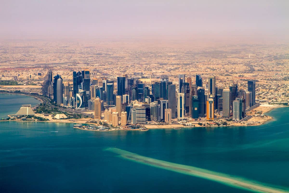 Luftaufnahme der modernen West-Bay-Skyline von Doha mit Luxushochhäusern und dem blauen Wasser der Bucht – ein eindrucksvolles Bild der gehobenen Atmosphäre der Stadt.