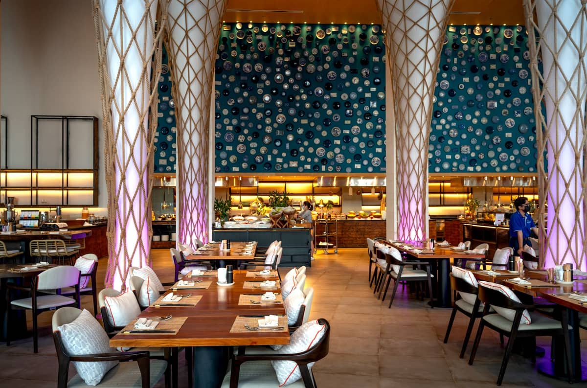 Elegantes, geräumiges Restaurantinterieur mit moderner Einrichtung, hohen Säulen und wunderschön gedeckten Tischen, das ein luxuriöses Dining-Erlebnis andeutet.
