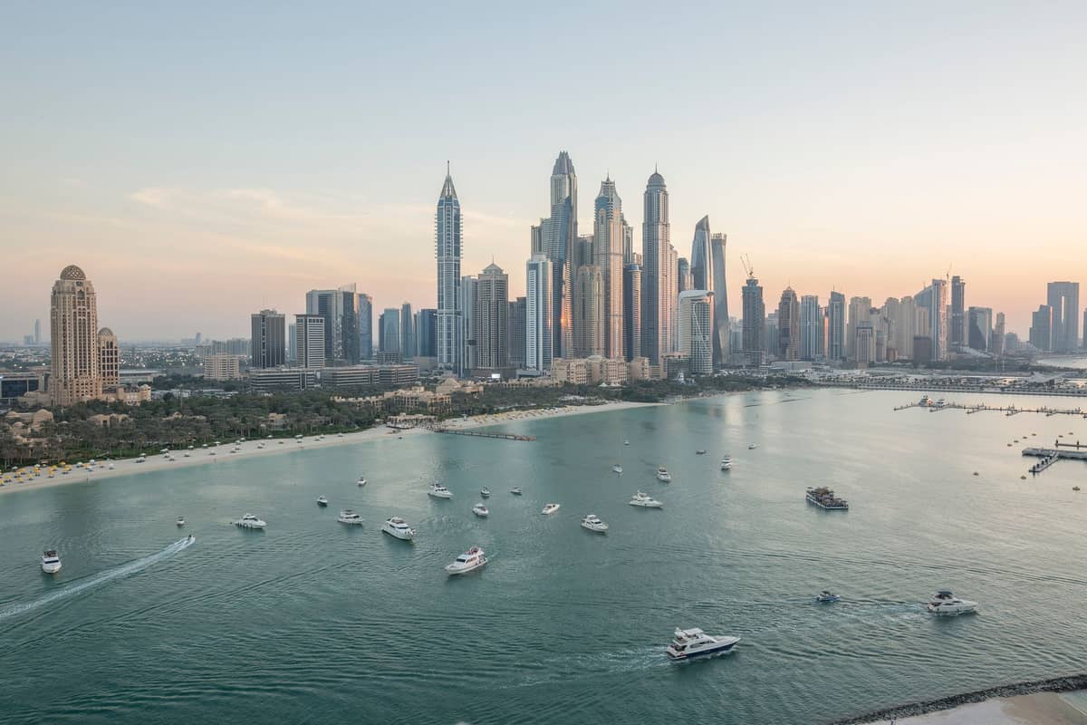Weitblick auf die Dubai Marina mit luxuriösen Wolkenkratzern, Yachten und einem Sandstrand im Vordergrund, der den exklusiven Waterfront-Lebensstil der Stadt zeigt.