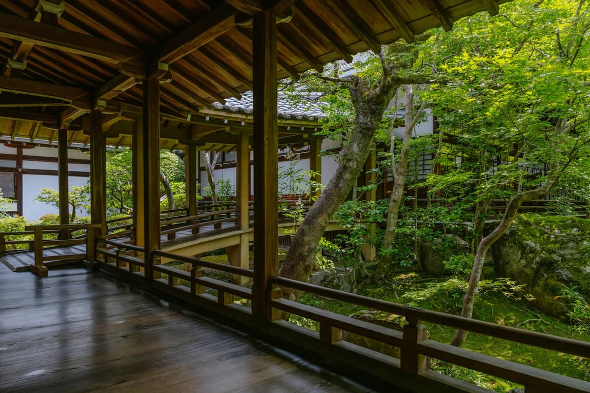 Traditional wooden corridor with an open view to a lush Japanese garden, typical of a ryokan in Kyoto.