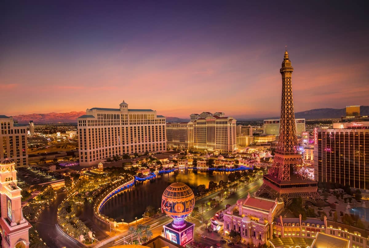 Vue aérienne du Strip de Las Vegas au coucher du soleil, avec les fontaines du Bellagio et le Paris Las Vegas avec la réplique de la Tour Eiffel, illuminés de lumières.