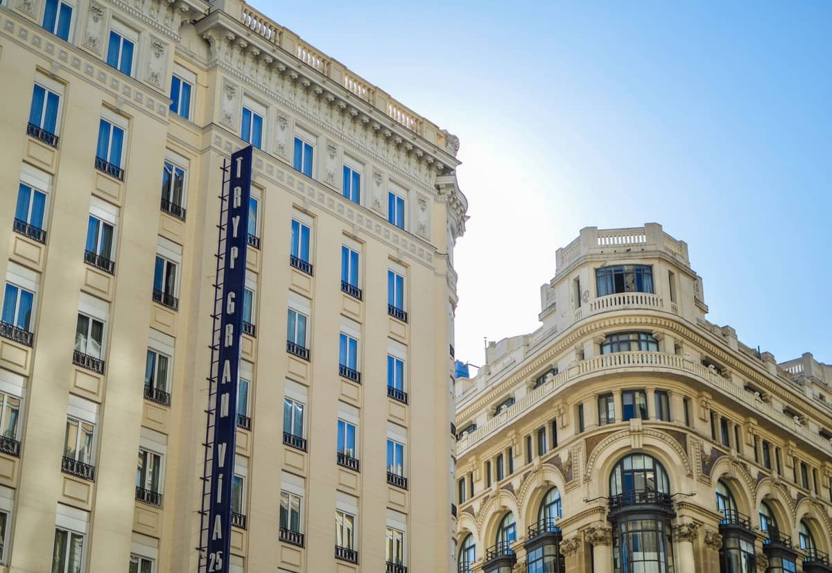 Elegante fachada del Hotel Gran Vía en Madrid con su arquitectura clásica bajo un cielo azul despejado.