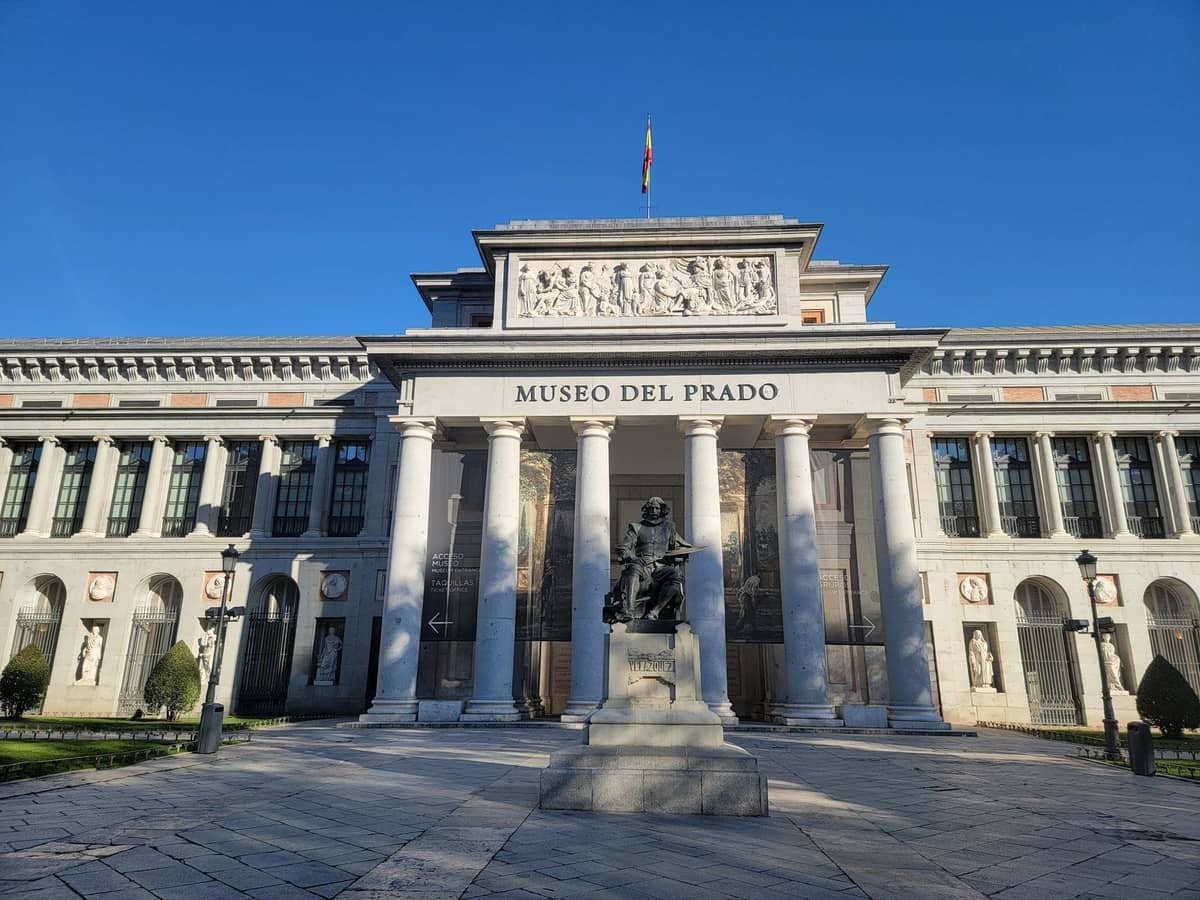 Fachada principal del Museo del Prado en Madrid con estatua y cielo azul despejado